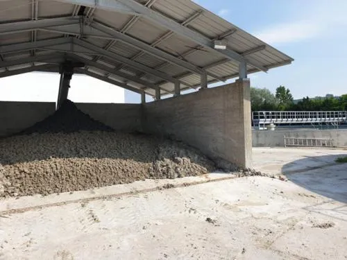 Pila de compost bajo una cubierta junto a una planta de tratamiento