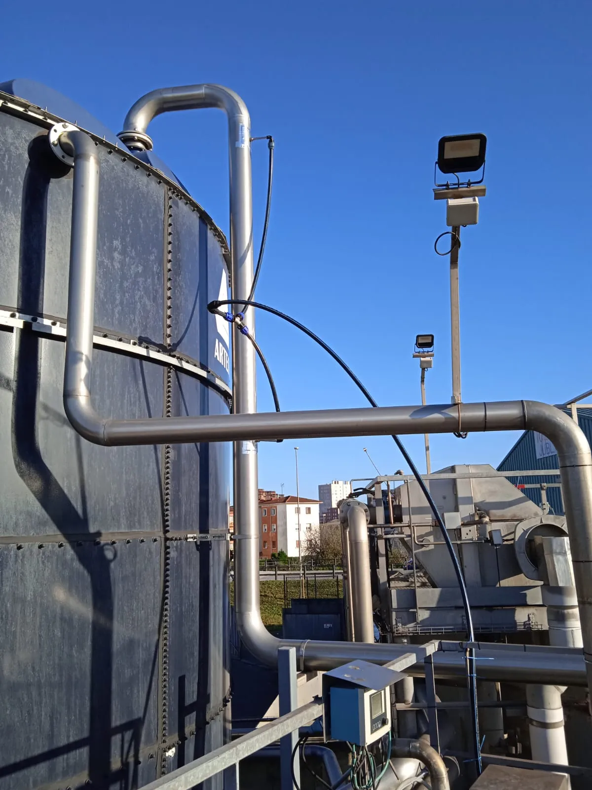 Tuberías de acero inoxidable de la línea de producto junto a un depósito metálico